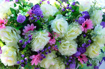 Composition of flowers of large beige roses, small purple roses and pink asters.