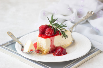 Classical vanilla cheesecake (New York cheesecake) with strawberry sauce and rosemary on white plate and light background