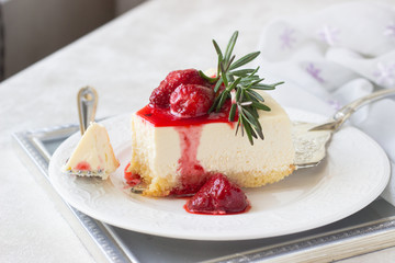 Classical vanilla cheesecake (New York cheesecake) with strawberry sauce and rosemary on white...