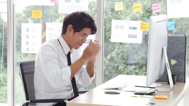 Annoyed asian businessman have a problem with him computer. stressed man having problem with broken computer at office.