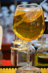 Glass of orange cocktail decorated with lemon at bar counter background.