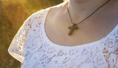 Chain with a cross on a neck . Christian cross on sunset background .  Religion background ....