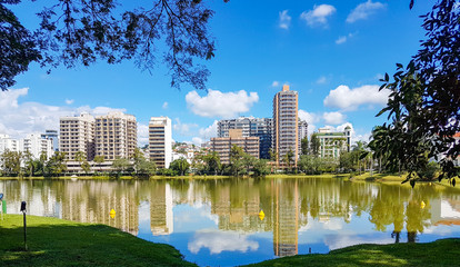 Fototapeta premium Dia ensolarado, lago refletindo o céu e os prédios