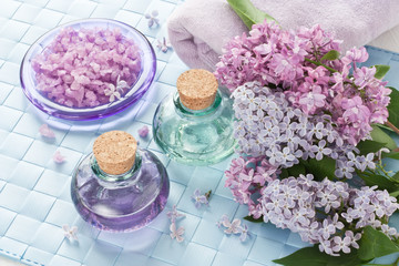 Obraz na płótnie Canvas Aromatherapy essential oil / Aromatherapy essential oil in glass bottle, sea salt, towel and lilac flower for SPA