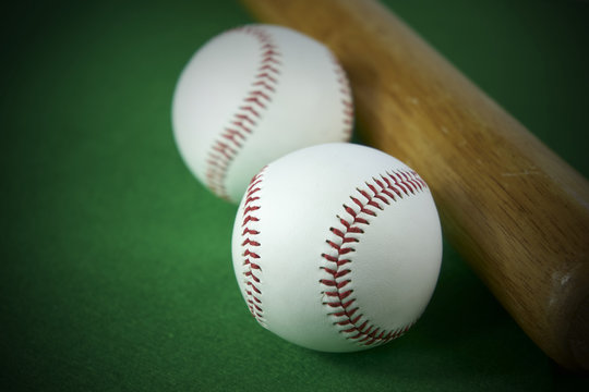 Two White Baseball ball and wooden bat isolated on green felt background
