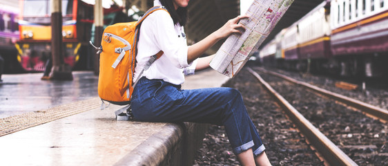 Girl wearing backpack holding map, waiting for a train. Traveling in Bangkok Thailand. Travel concept - Powered by Adobe