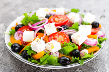 Greek salad. Fresh vegetable salad with tomato, onion, cucumbers, pepper, olives, lettuce and feta cheese. Greek salad on plate