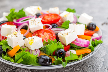 Greek salad. Fresh vegetable salad with tomato, onion, cucumbers, pepper, olives, lettuce and feta cheese. Greek salad on plate