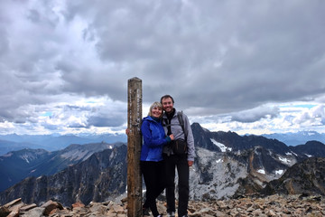 Happy married couple outdoors on mountain top smiling and hugging. People hiking in British Columbia near Vancouver. Mount Frosty. Manning park. Hope. BC. Canada.