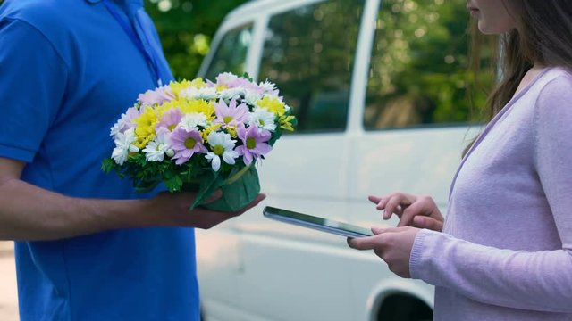 Courier delivering flowers woman, tablet signature, birthday present family care