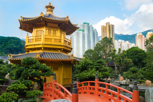 Golden Pagoda in Nan Lian garden, with red bridge and surrounded by green plants. The Hong Kong Skyline is in the background.