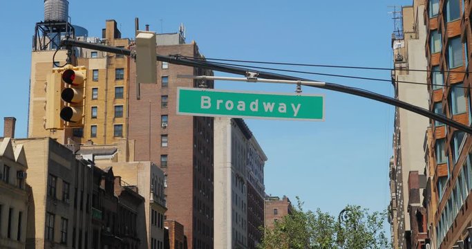 A daytime establishing shot of a Broadway street sign.  	