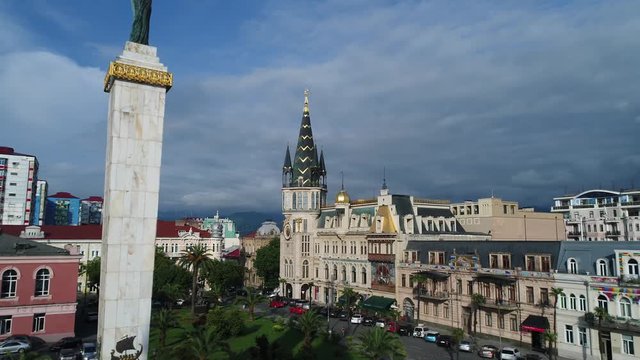 Flying over Europe square in Batumi past the statue of Medea to a beautiful tower with an astronomical clock. it offers stunning views of the city in cloudy weather. Aerial view.