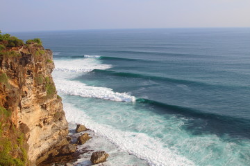 Fototapeta na wymiar Perfect waves roll in from my cliff overlook in Bali