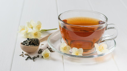 Freshly prepared tea with Jasmine flowers on a white rustic table.