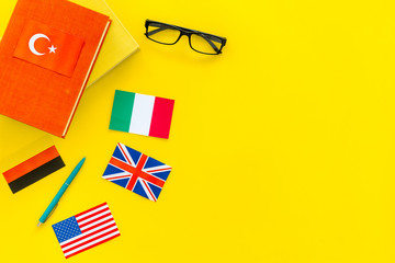 Language study concept. Textbooks or dictionaries of foreign language near flags on yellow...