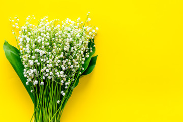 Small and fragrant spring flowers. Bouqet of lily of the valley flowers on yellow background top view copy space