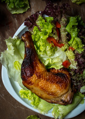 A dish of Roasted Chicken Thigh with fresh vegetable on wooden table. Closeup photo food.