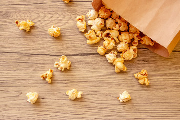 Sweet popcorn in brown paper bag on the wooden table. The closeup food photo