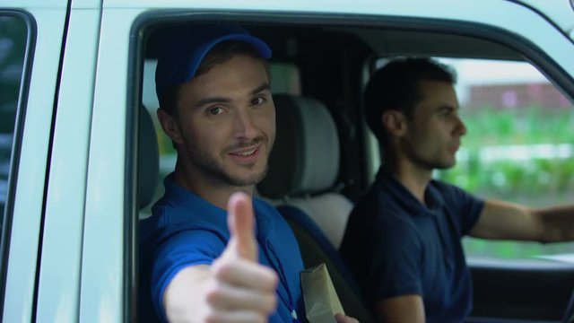 Young delivery man in van holding parcel showing thumbs up, express shipment
