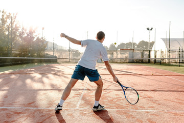  Man playing tennis in the morning in sunlight