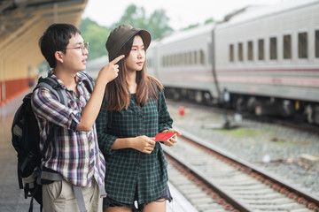 Backpacker woman and man at the train station with a traveler.Couple Travel concept.