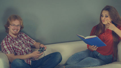 Woman playing games man reading book