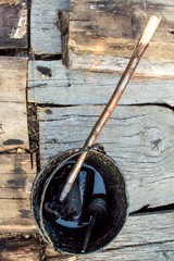 A bucket of black tar boils on the fire for use in repair and waterproofing.