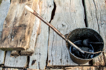 A bucket of black tar boils on the fire for use in repair and waterproofing.
