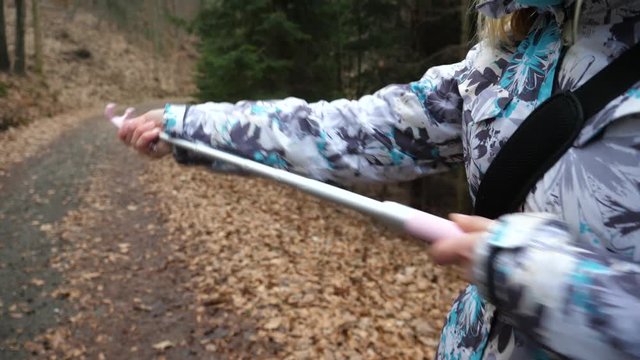 Girl extending the selfie stick for taking pictures walking on nature forest