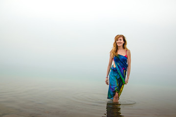 Nice woman stands in water of Dead Sea in Jordan and fog