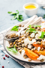 Lentil, roasted vegetables and goat cheese salad on light blue background. Selective focus, copy space.