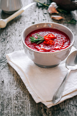 Beet cream soup with rosemary, garlic and chili on wooden background