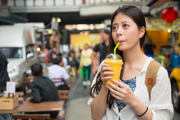 Obraz premium woman drinking the mango juice in the street