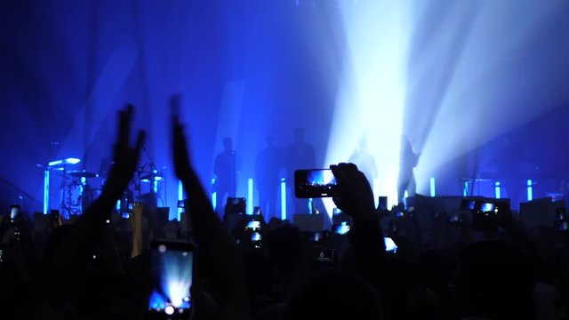 Concert crowd people clap hands shoot mobile phone video near the stage with singer