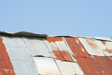 Wooden house with rusty zinc roof on blue sky background