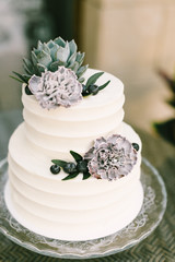Elegant white wedding cake with flowers, blueberries and succulents