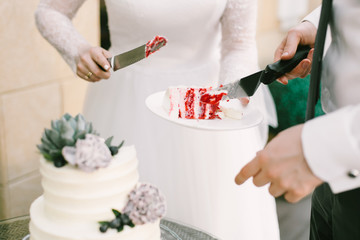 A bride and a groom cutting their white wedding cake with red filling