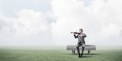 Handsome businessman in park on wooden bench play his melody