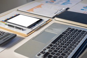 Office desk table with pen, keyboard on notebook, cup of coffee and flower. Top view with copy space (selective focus).