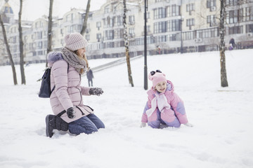 Happy loving caucasian family of mother father and daughter play, having fun in winter snowy park. Cute little girl playing