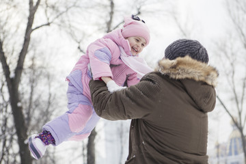 Happy loving caucasian family of mother father and daughter play, having fun in winter snowy park. Cute little girl playing