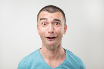 Obraz premium surprised young man in polo t-shirt over gray background.