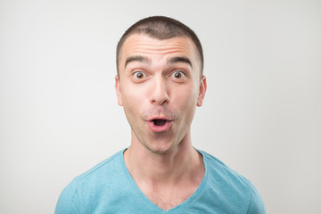 Obraz premium surprised young man in polo t-shirt over gray background.