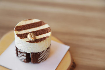 Tiramisu cake recipe with golden coffee bean decorated on top on wooden plate.