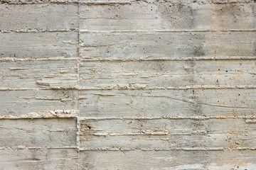 Texture of wooden formwork stamped on a raw concrete wall as background.