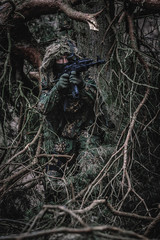 Airsoft player in eastern uniform during playtime in forest