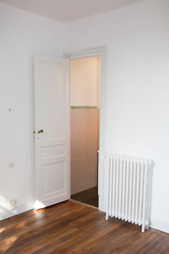 empty room with an old wooden floor and a white door and a radiator
