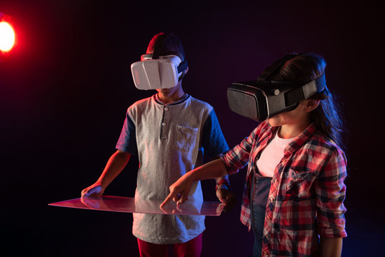 Our day off. Adorable joyful girl and a boy wearing VR headsets and touching a screen