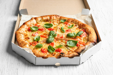 Carton box with delicious pizza Margherita on wooden background